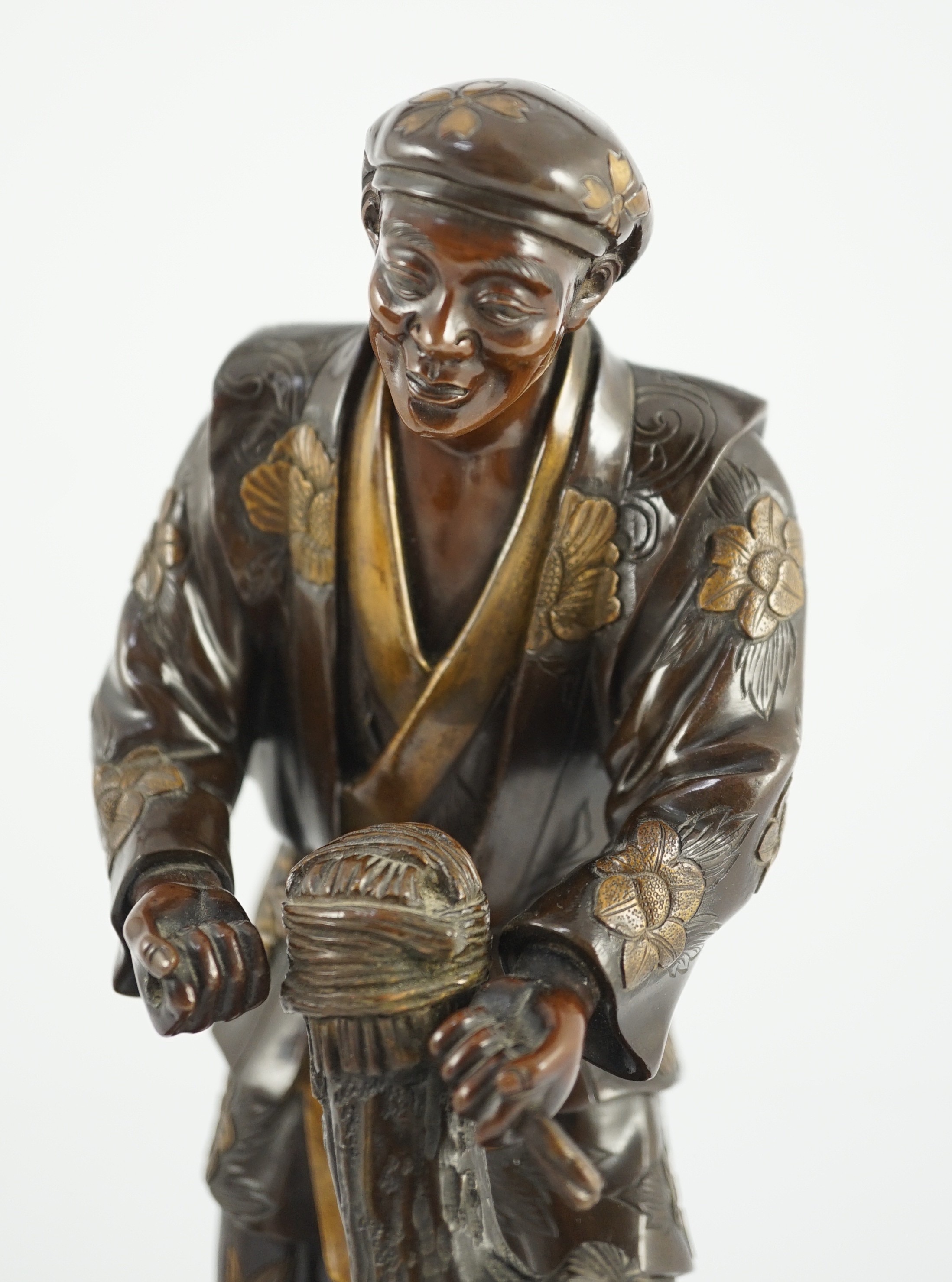 A Japanese brown patinated and gilded bronze figure of a woodworker, in Miyao style, Meiji period, 27.5cm high